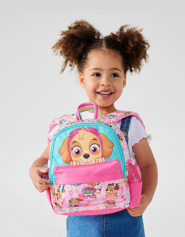 Little girl smiling while holding a Smiggle Paw Patrol Skye Teeny Tiny Backpack featuring Skye character design